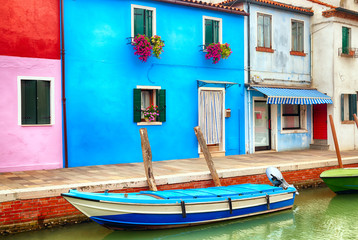 Fototapeta na wymiar Colorful houses in Burano near Venice, Italy with a boat. Famous tourist attraction in Venice. Picture of canal and fishing boat