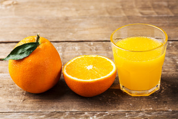 Fresh orange juice and oranges on wooden table