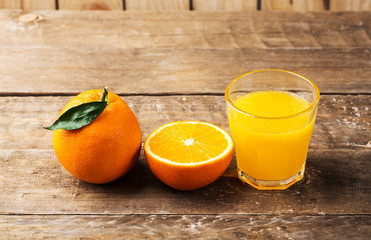 Fresh orange juice and oranges on wooden table