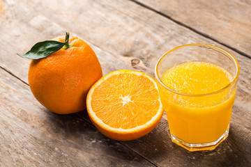 Fresh orange juice and oranges on wooden table