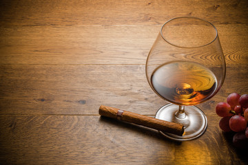 Glass of cognac and cigar with snack on the wood table with stone cutting board. Top view with copy space