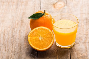 Glass of orange juice and fruits on wooden background