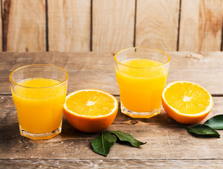 Orange juice. Glasses of orange juice and fruits against wooden background