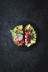 Healthy food. Avocado sandwiches with avocado slices, seeds and sprouts on dark background.