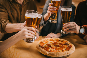 cropped view of friends toasting glasses of beer in bar