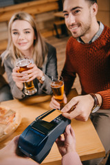 selective focus of man paying by credit card while cashier holding terminal in hands