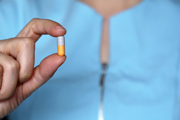 Doctor holding pill, capsule in female hand close-up. Woman with tablet, concept of medication, pharmacist, drugs, antibiotics or diet pill