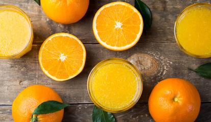 Top view of freshly pressed orange juice and oranges on wooden table