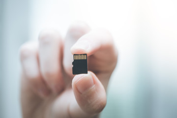 Young man is holding a tiny memory card in his hand, text space