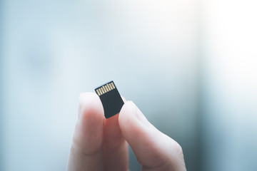 Young man is holding a tiny memory card in his hand, text space