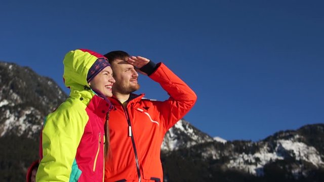 The guy and the girl on vacation in a ski resort. Couple looks into the distance, putting his hands to his forehead, closing from the sun