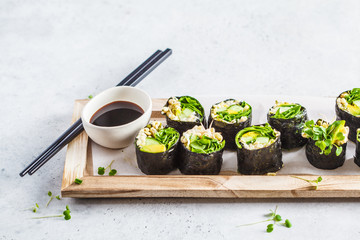 Green vegan sushi rolls on wooden board.