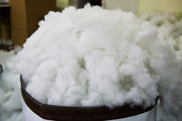 Modern bio-polymeric synthetic filler  for fabric toys on toy factory. White synthetic fabrics...