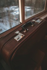 Vintage old suitcase standing on the windowsill in front of the window at sunset