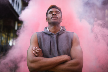 Serious confident handsome young black athlete with mustache crossing arms on chest and looking...