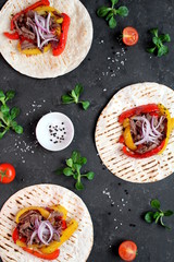 Tortillas flat various vegetables and beef for tacos or burrito on dark background. Top view with copy space.