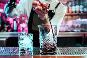 Expert barman is making cocktail at night club or bar. Glass of fiery cocktail on the bar counter against the background of bartenders hands with fire. Barman day concept