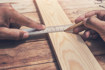 close up carpenter making measurements on the wooden plank