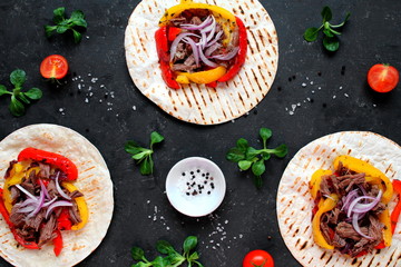 Tortillas flat various vegetables and beef for tacos or burrito on dark background. Top view with copy space.