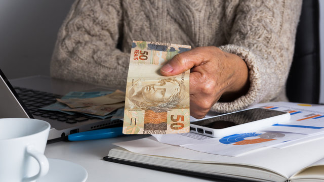 Paper notes from Brazil. Woman holding bills on desk office.