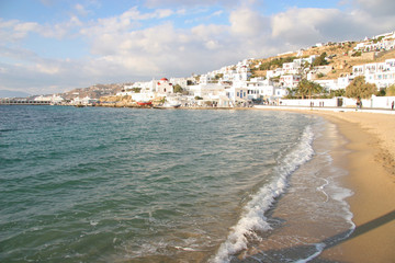 Beautiful sand beach in the foreground, with a typical church in the distance, Mykonos town, Cyclades, Greece.