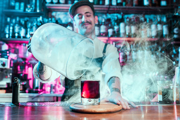 Expert barman is making cocktail at night club or bar. Glass of fiery cocktail on the bar counter...