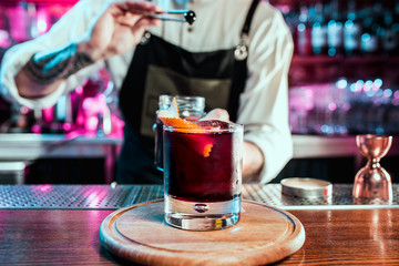 Expert barman is making cocktail at night club or bar. Glass of fiery cocktail on the bar counter...