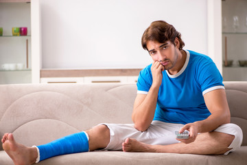 Leg injured young man on the sofa