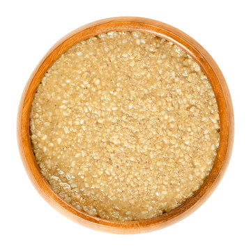 Homemade tahini, sesame paste, in wooden bowl. Brown condiment made of ground hulled sesame seeds. Dip or major ingredient in hummus, baba ghanoush and halva. Food photo closeup, on white background.
