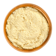 Hummus in wooden bowl. Levantine dip or spread made from cooked, mashed chickpeas, blended with tahini, olive oil, lemon juice, cumin, salt and garlic. Food photo, closeup, from above, over white.