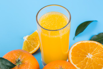 Glass of orange juice and slice of orange fruit on blue background