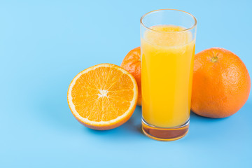 Orange juice and fresh oranges on blue background