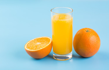 Orange juice and fresh oranges on blue background