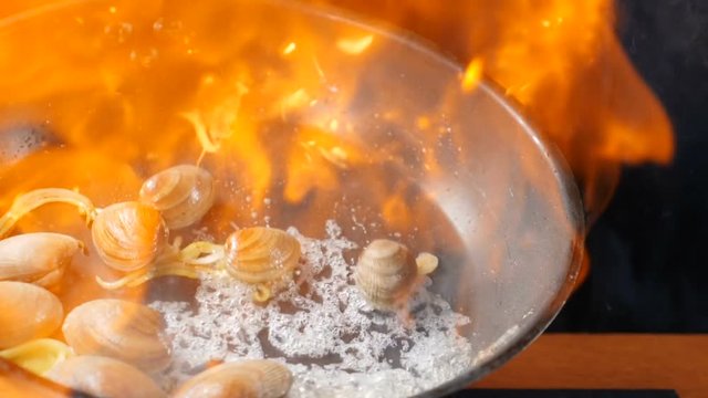 Restaurant food cooking. Chef cooking Italian Seafood pasta flambe using Shrimp, Clams, Mussels in dish. Italian cuisine concept. Slow motion hd