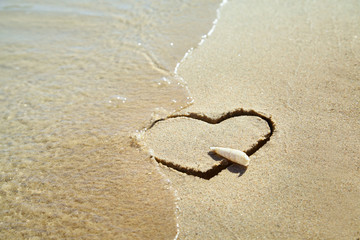 Obraz na płótnie Canvas Heart made of sand on the beach. Love concept. Shell is the symbol of arrow