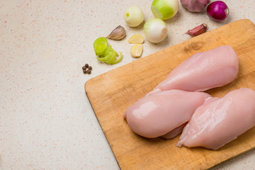 Raw chicken fillet with garlic, pepper and on a wooden cutting board.