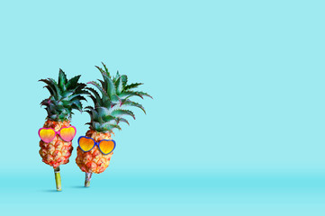 Minimal summer concept design of pineapple wearing sunglasses on blue background