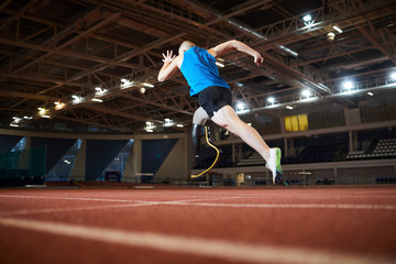Rear view of paralympic runner over race track moving forwards during marathon at stadium