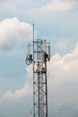 technicians working on communication pole  against with cloudy sky. vertical photo.