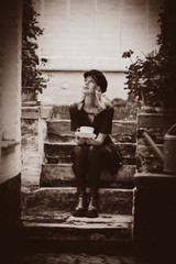 Young style girl dress and hat with cup of coffee autumn season garden in Belgium. Image in sepia color style