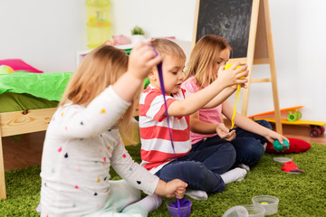 childhood, leisure and people concept - children playing with modelling clay or slimes at home