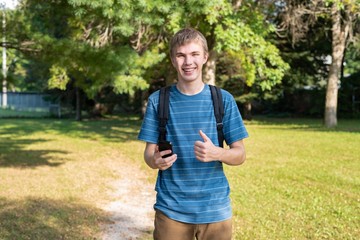 Teenager on his cellphone while standing in a city park on a summer day.