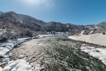 Shogawa river  in Shirakawago village with snow covered ground ,blue sky and mountains background at winter in Gifu,Japan.