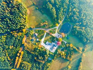 Farm or house in autumnal forest, top down aerial landscape