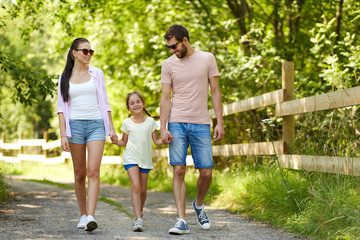 family, leisure and people concept - happy mother, father and little daughter walking in summer park