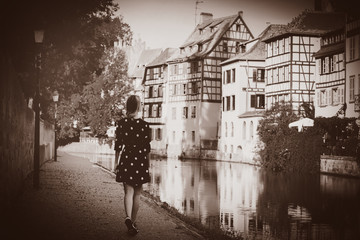 Young style girl in black dress waking along the canal in Strasbourg, France. Autumn season time