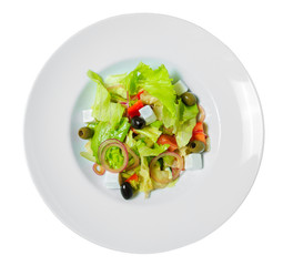 Greek salad with olives, onion, feta cheese, romaine lettuce and tomatoes on a plate.