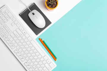 Computer keyboard and mouse on color block background, office interior