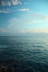 Fototapeta premium Aerial top view of sea waves hitting rocks on the beach with turquoise sea water. Amazing rock cliff seascape in the coastline. Aerial view of sea waves and fantastic Rocky coast. Mediterranean Sea.