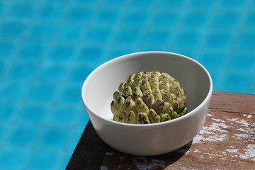 Near the pool in a plate is an sugar apple